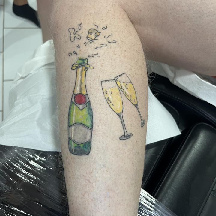 Farbiges Sekt-Motiv am Unterschenkel — Tattoo Funny Pain
